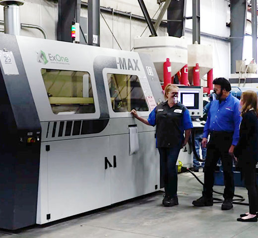 Workers at Humtown Additive walk past an industrial 3D printer