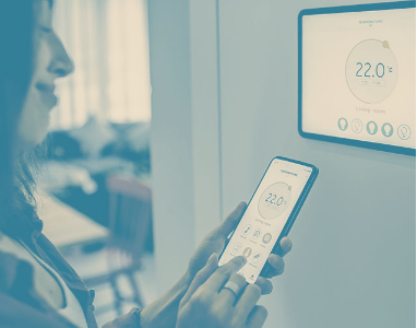 Photo of a woman controlling a thermostat with her smartphone